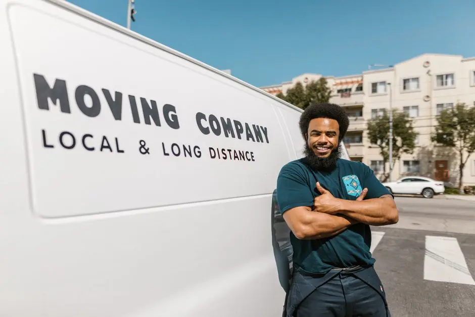 A cheerful mover standing confidently beside a moving company’s van, ready for local or long distance relocation services.