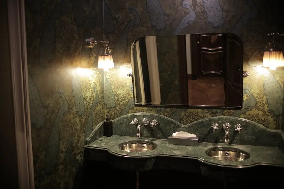 Luxurious bathroom featuring twin sinks with elegant green marble countertops and decorative wallpaper.
