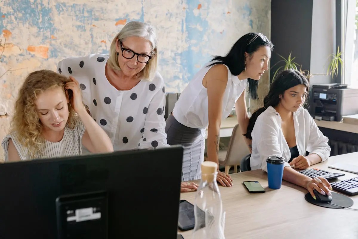 A group of women collaborating in a contemporary office setting, engaging in teamwork and discussion.