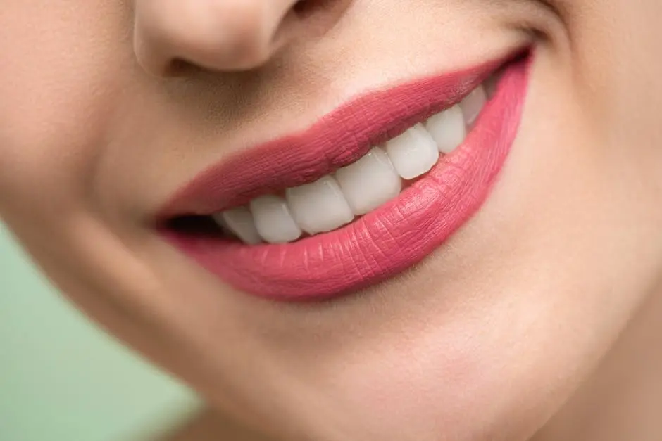 Vivid close-up image of a woman&rsquo;s smile showcasing red lipstick and white teeth on a light background.