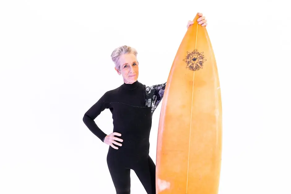 Elderly woman in wetsuit holding surfboard, embracing active lifestyle and healthy living.
