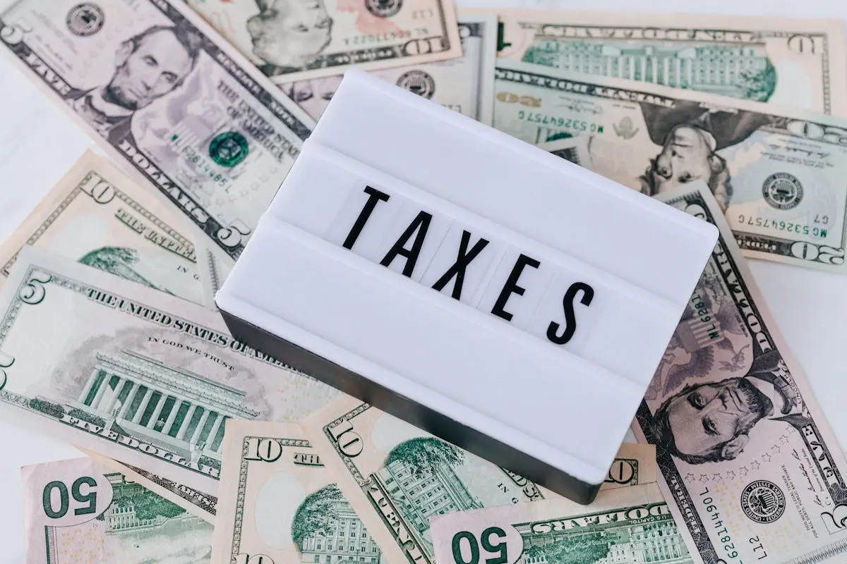 US dollar bills surrounding a sign showing taxes Ideal for business acquisitions.