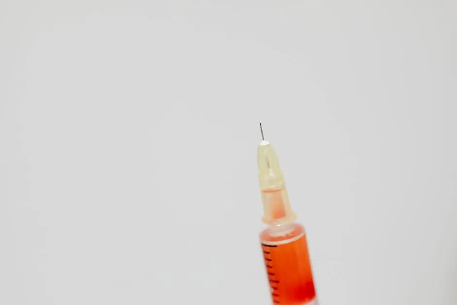 Detailed image of a syringe needle with red liquid against a soft background.