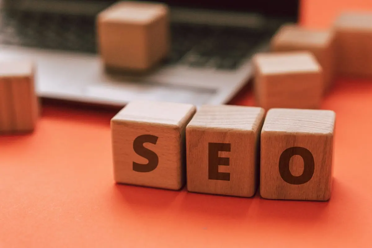 Wooden blocks spelling SEO on a laptop keyboard convey digital marketing concepts & brand enhancement