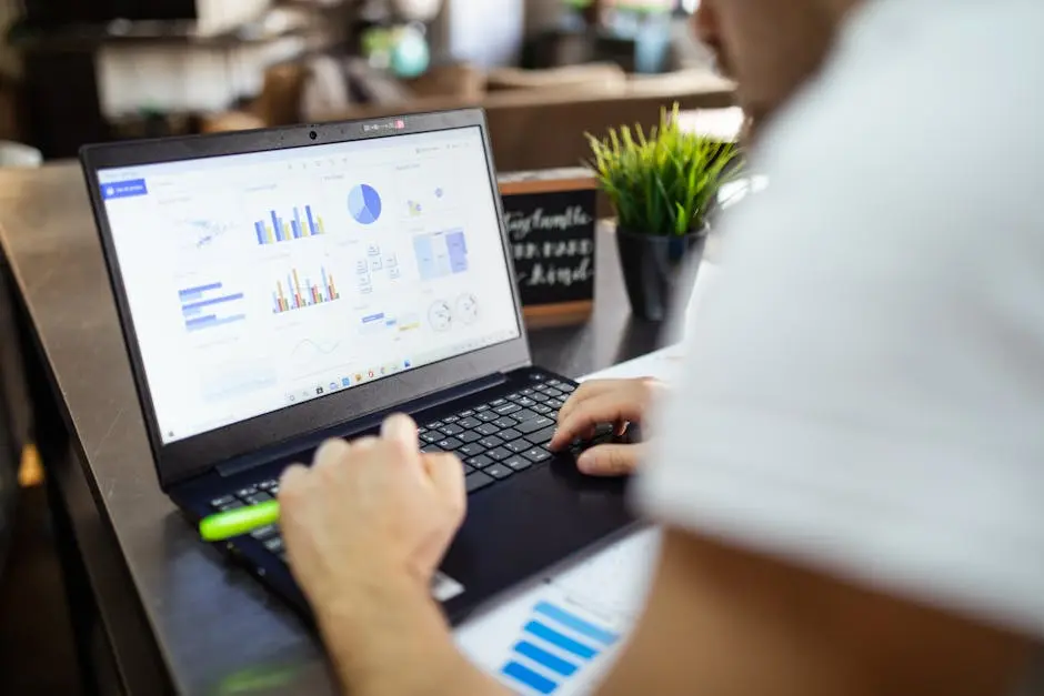 Focused business analysis with charts and graphs on a laptop in a modern office setting.