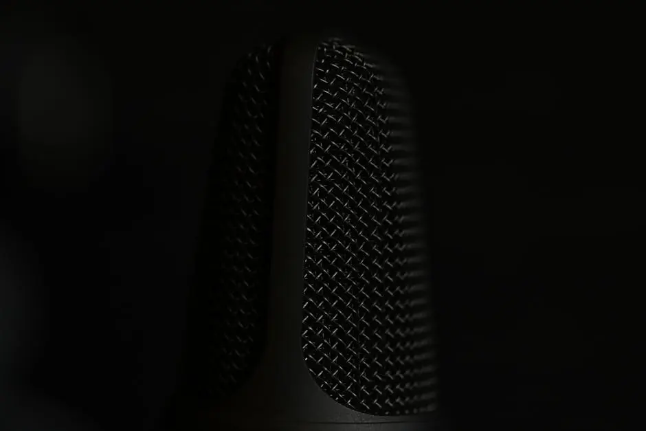 A detailed macro shot of a microphone in a studio setting with a dark background.