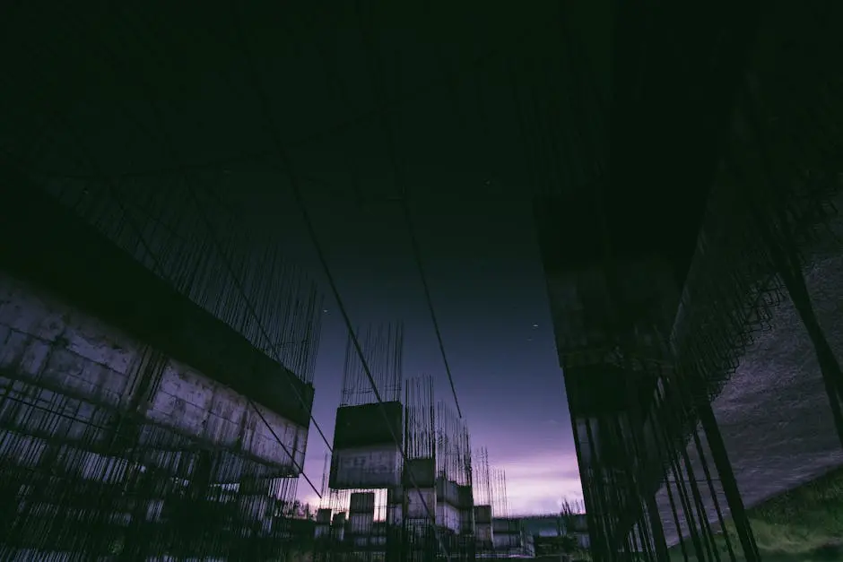 Silhouette of an urban construction site at twilight, capturing steel structures against a darkening sky.