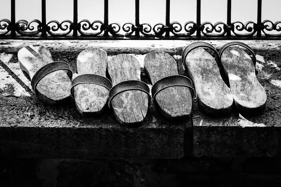 Artistic black and white image of wooden sandals on a stone ledge.