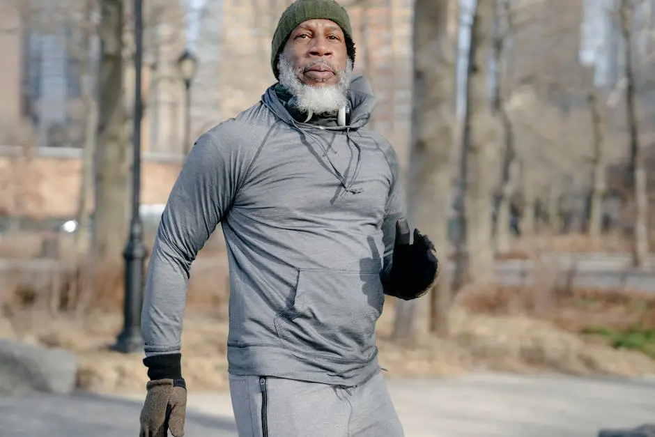 Elderly man exercising outdoors in winter, wearing gray sweater and beanie.