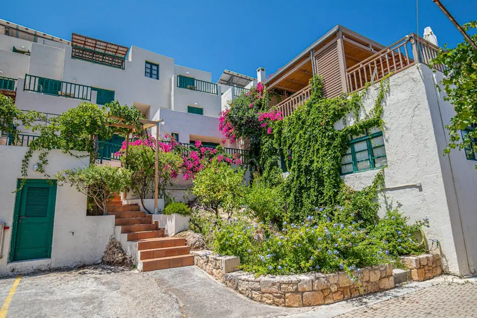 Mediterranean villa adorned with lush greenery and vibrant flowers, under a clear blue sky.
