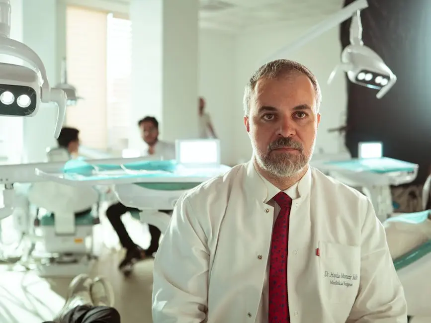 A dentist in a white coat sits in a modern dental clinic, surrounded by equipment and assistants.