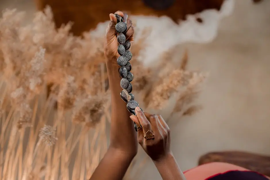 A close-up of hands holding a handcrafted beaded necklace against a soft background.