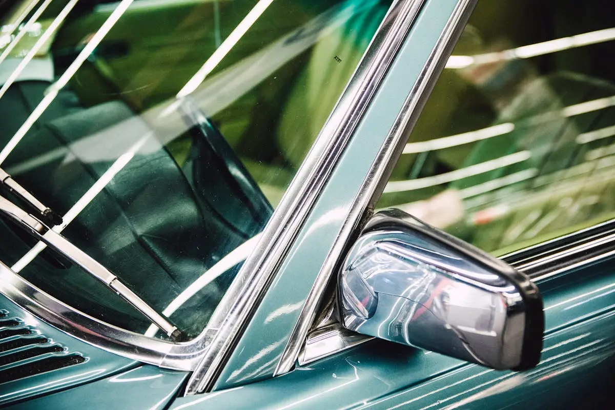 Detailed image of a luxury car’s side mirror, window, and chrome trim.