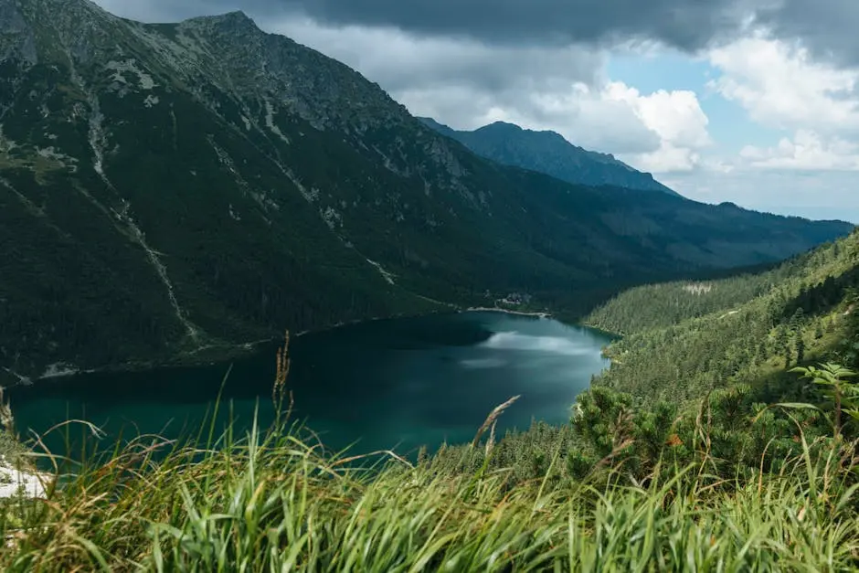 Majestic view of a serene lake surrounded by Tatra Mountains under a cloudy sky in Poland.