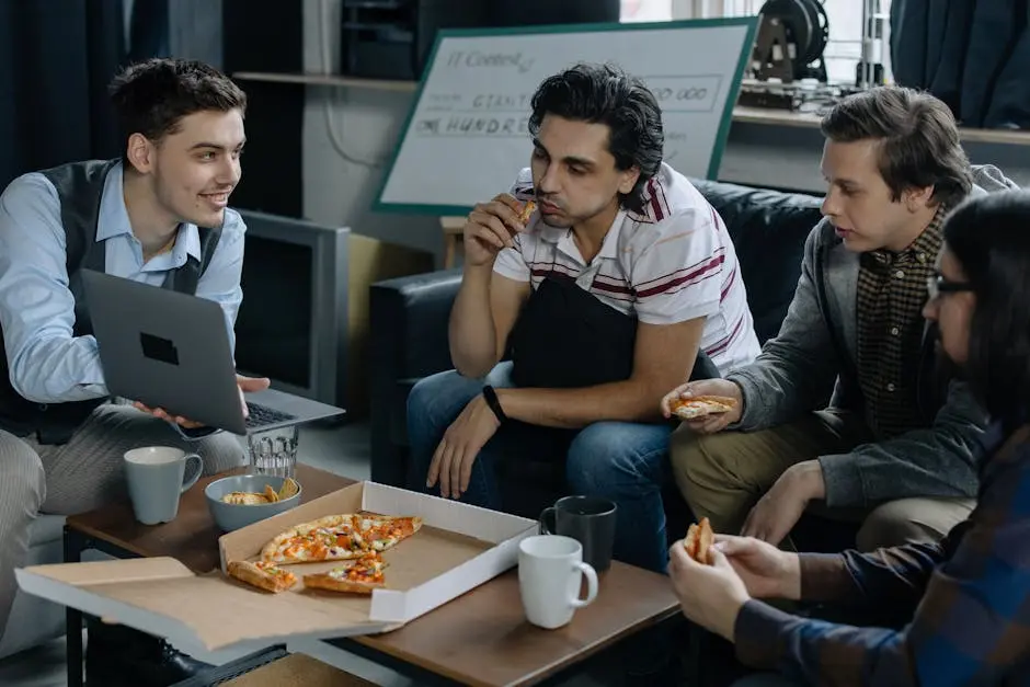 Group of young men having pizza and discussing ideas during a startup meeting in a casual setting.