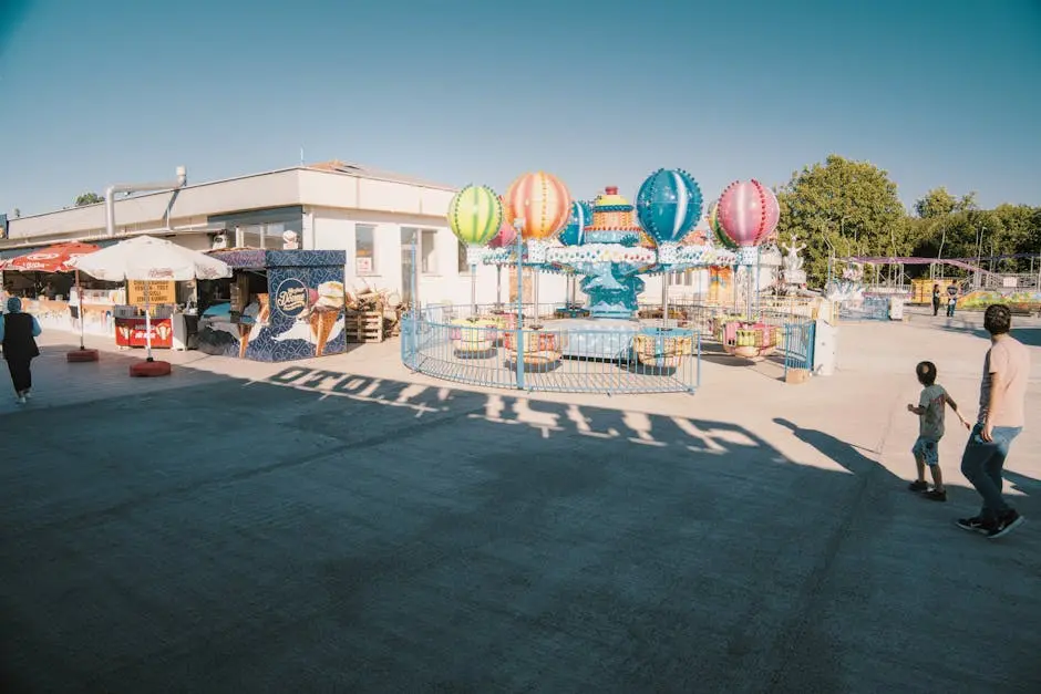 Colorful carnival scene with balloon ride and visitors enjoying a sunny day outdoors.
