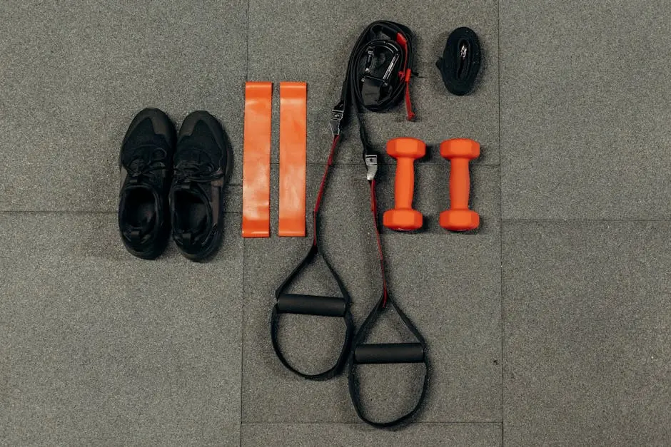 Flat lay of fitness gear including dumbbells, sneakers, and resistance bands for a home workout.