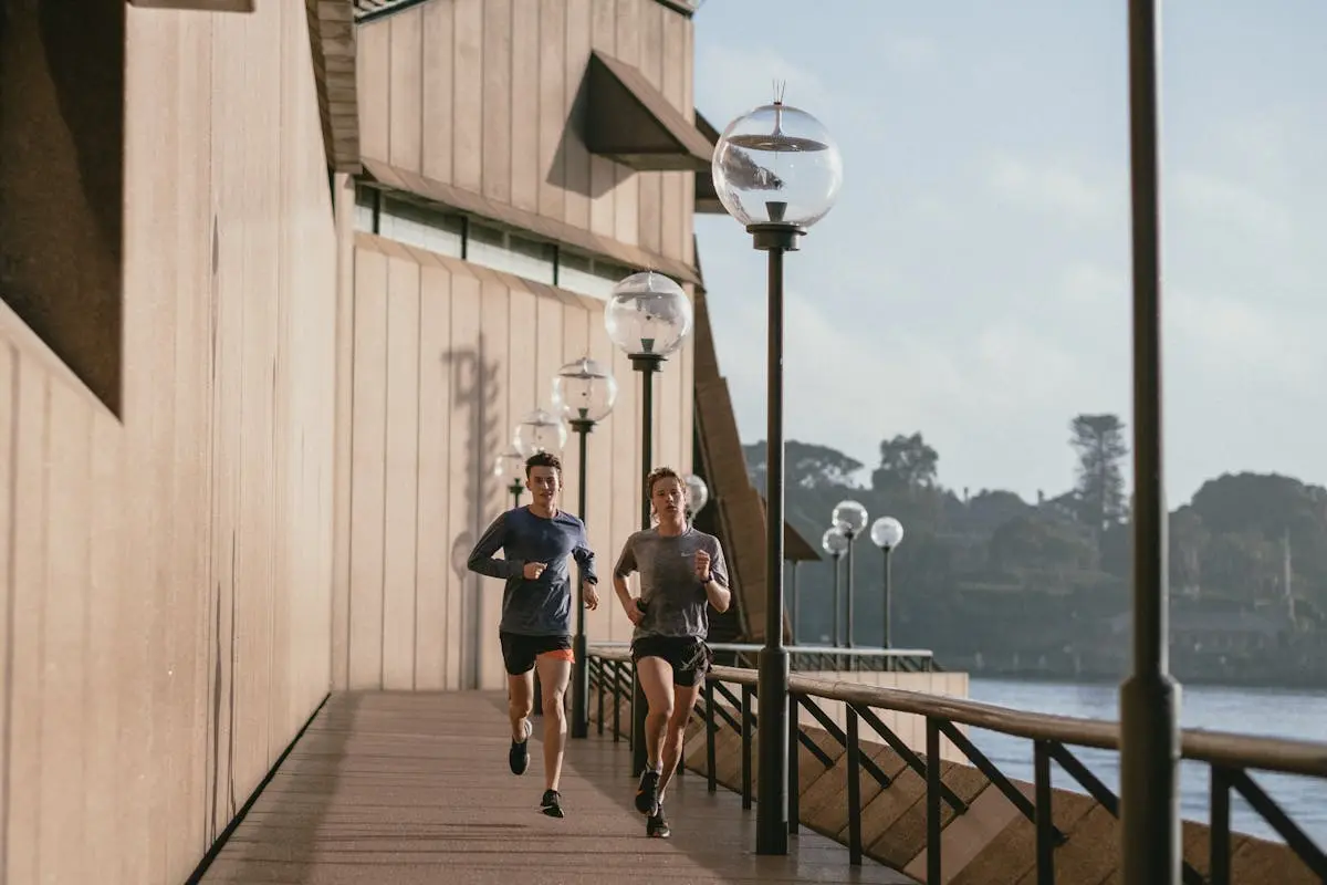 Two people jogging by the Sydney Opera House on a sunny day, capturing a healthy lifestyle.