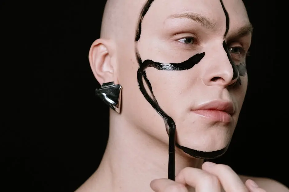 Creative portrait of a person with bold face paint and metallic earring on a black background.