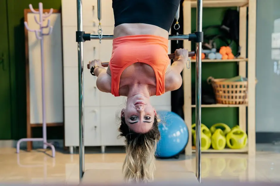 Woman practicing inverted Pilates on a reformer at a gym, focused on fitness and flexibility.