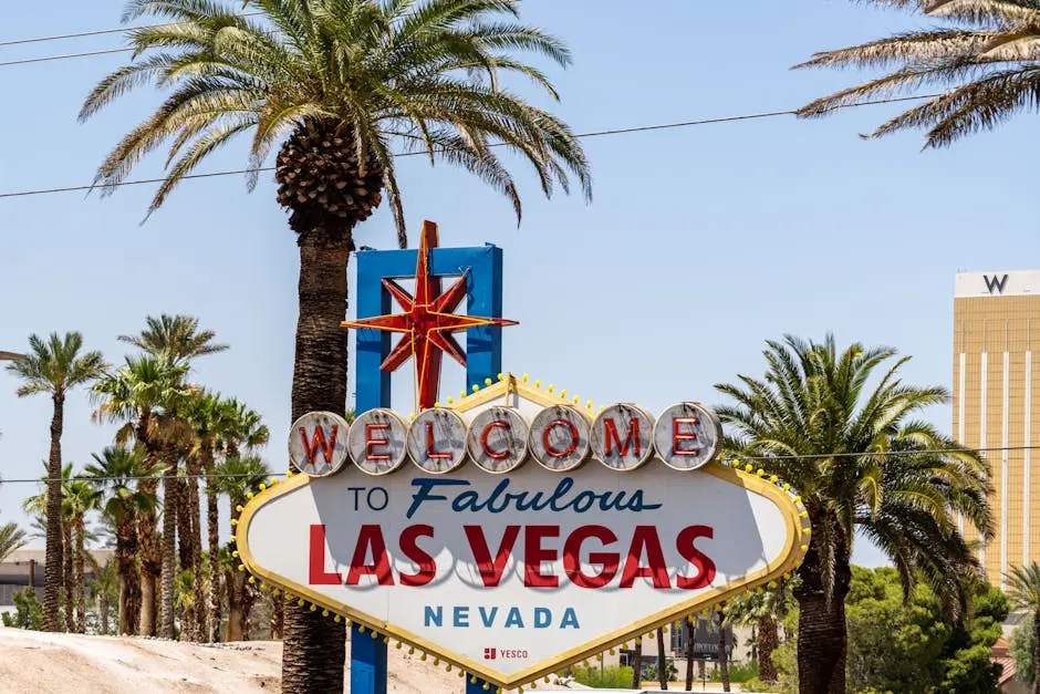 The classic &lsquo;Welcome to Las Vegas&rsquo; sign amidst palm trees, under a bright blue sky.