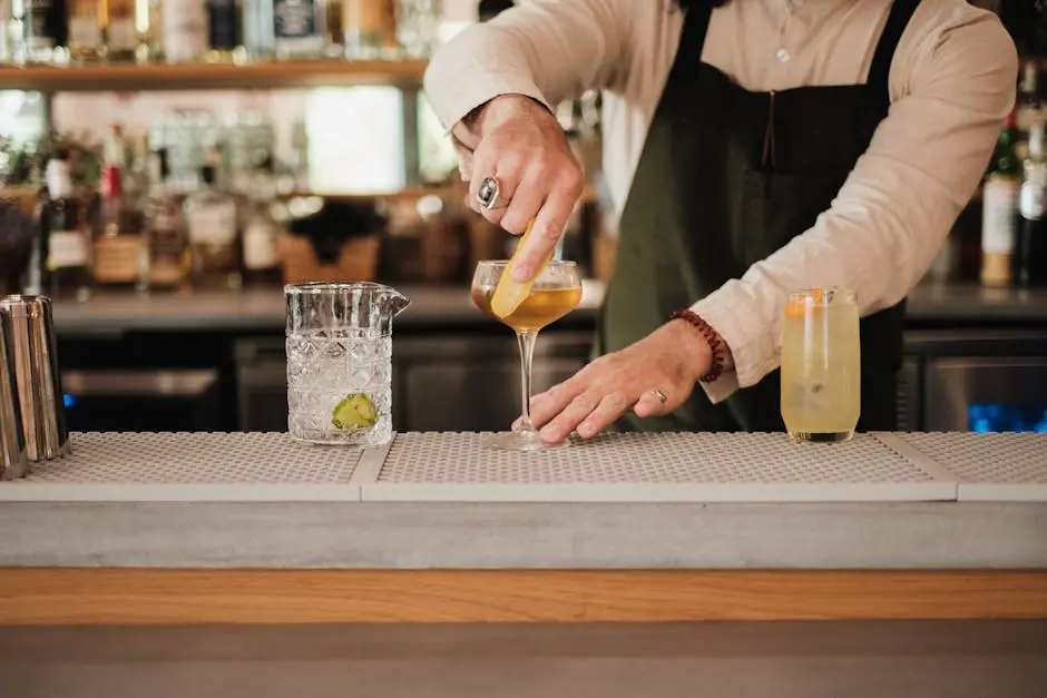 Bartender in apron garnishing cocktails at an upscale bar counter.