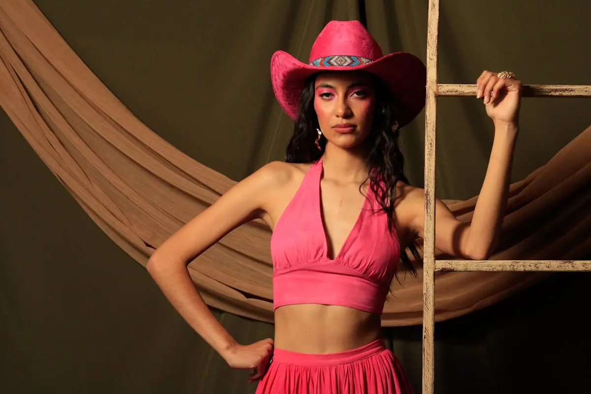 Elegant cowgirl in a vibrant pink outfit posing confidently indoors.