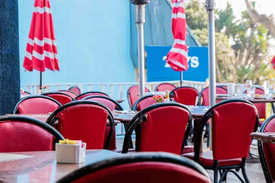 A lively outdoor restaurant setting with red chairs and parasols, perfect for dining al fresco.