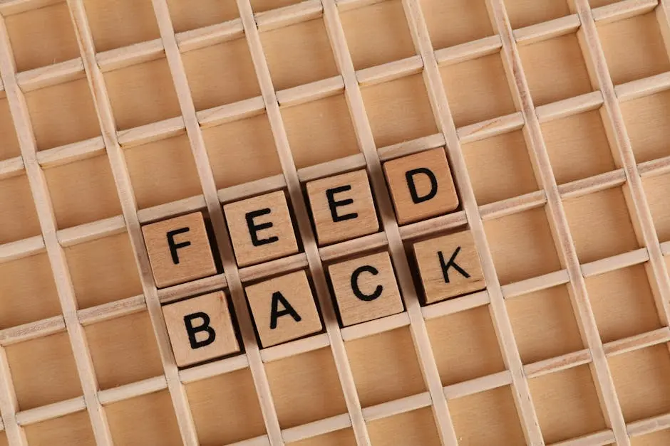 Wooden letter blocks spelling &lsquo;Feedback&rsquo; on a wooden grid surface.