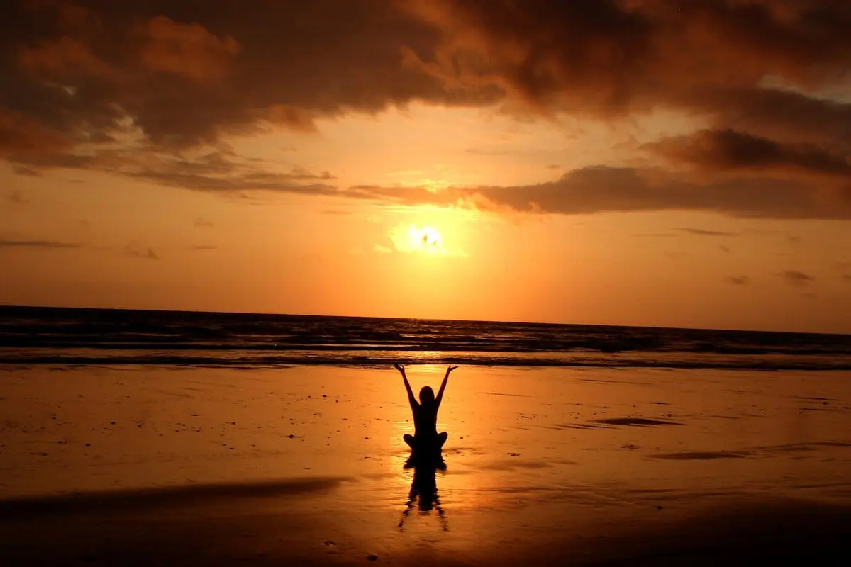 Peaceful meditation silhouette at sunset on a serene beach.