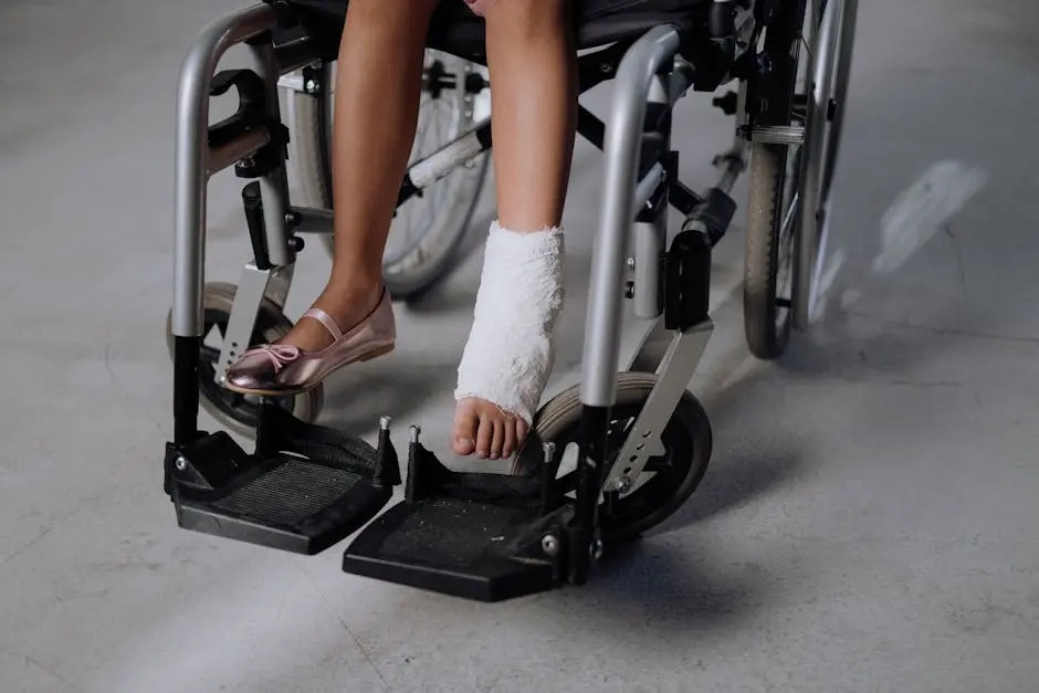 A close-up of a young girl’s bandaged leg in a wheelchair, highlighting recovery.