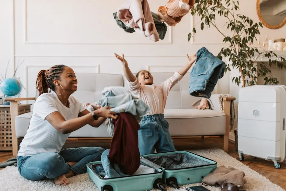 Mother and daughter joyfully packing clothes into a suitcase for a family trip.