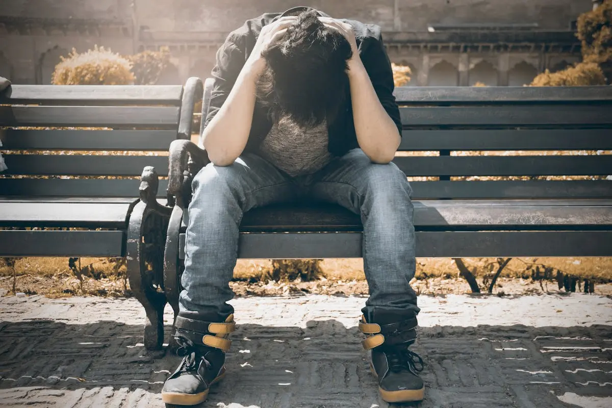 Man sitting alone on a bench in Agra, displaying signs of stress and loneliness.