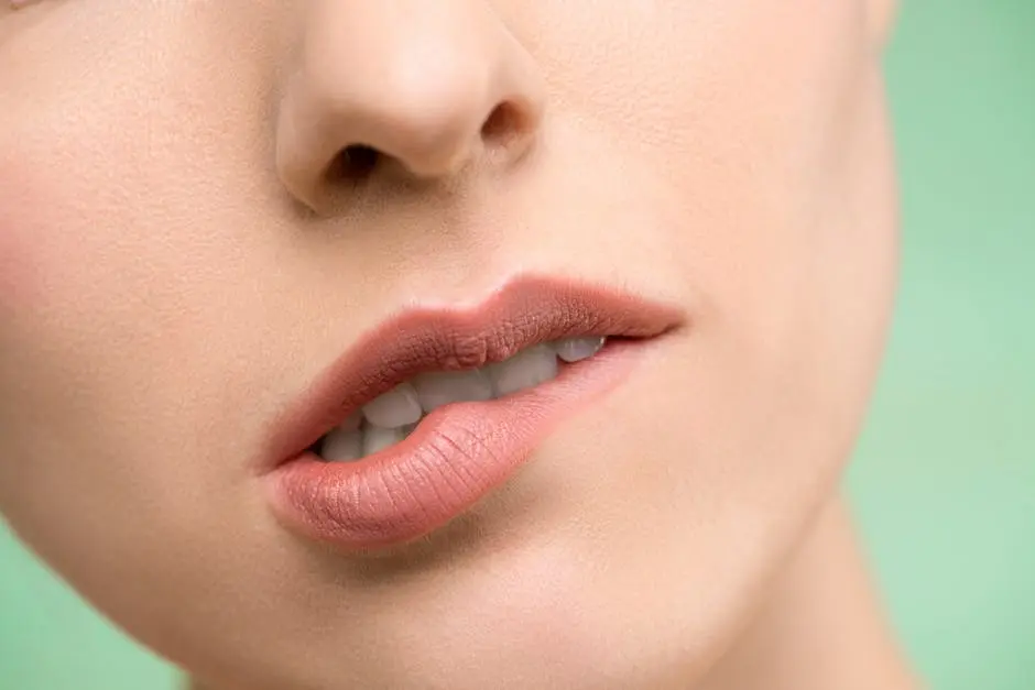 A close-up image showcasing a woman’s lips with natural makeup against a pastel background.