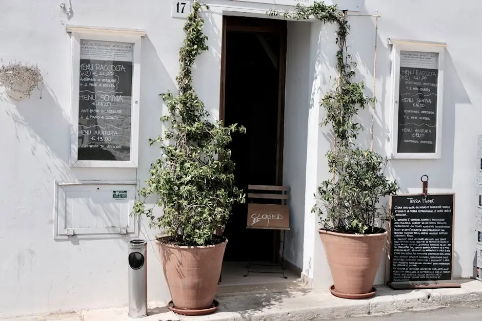 Explore the quaint entrance of an Italian restaurant, adorned with potted plants and menu boards.