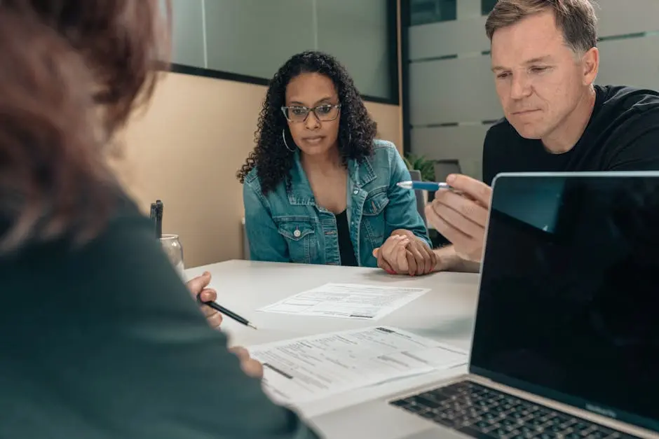 A couple reviewing documents with a professional in an office setting, focusing on financial planning.