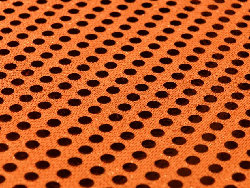 High-quality close-up image of orange dotted fabric showcasing a striking polka dot pattern.