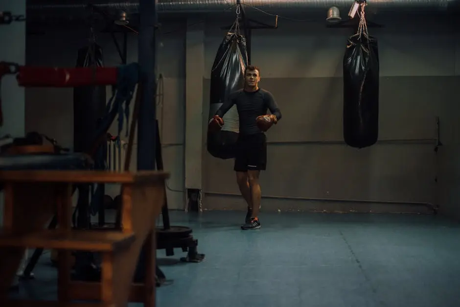 Male boxer trains in a gym with punching bags, wearing boxing gloves, focused and determined.