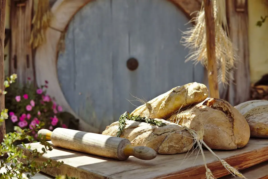 Freshly baked artisanal bread with a rolling pin on a rustic table outside a Hobbiton inspired door in New Zealand.