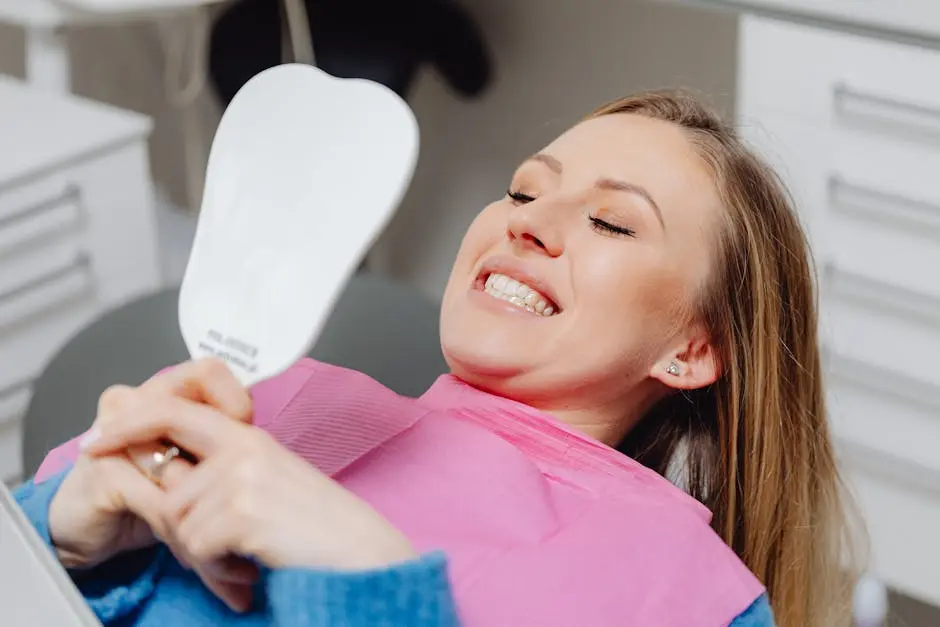 A woman at a dental clinic smiles while holding a mirror, showcasing her dental treatment results.